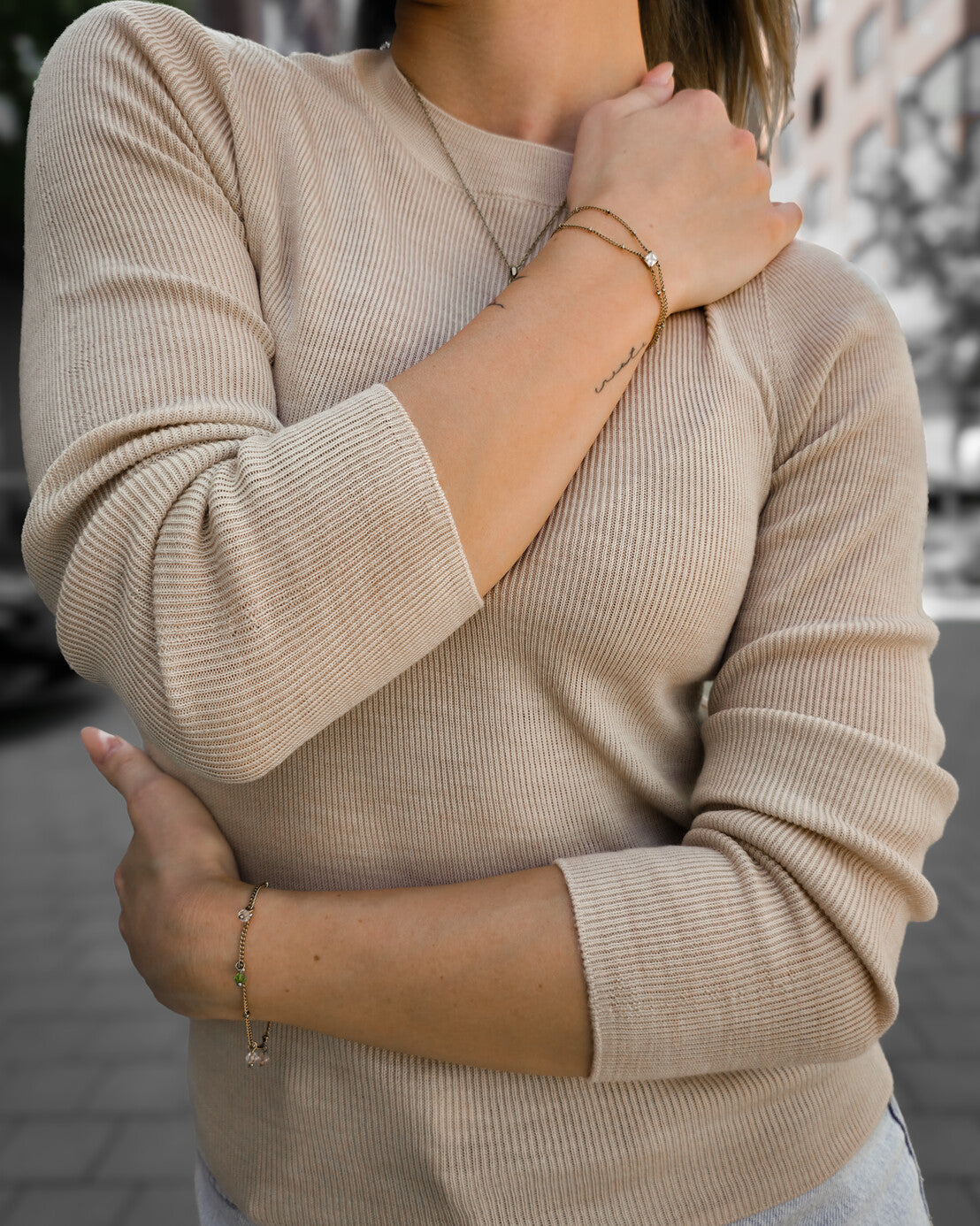 Detailansicht von Rundhalsausschnitt, Ärmel und feinem Strick des beigen Merino-Longsleeves.