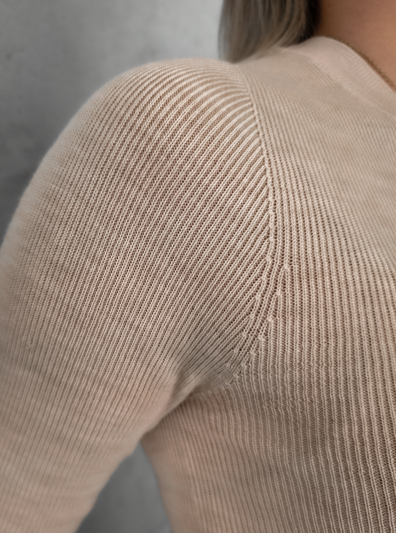 Nahaufnahme der Schulterverarbeitung und feinen Strickstruktur des beigen Merino-Longsleeves.